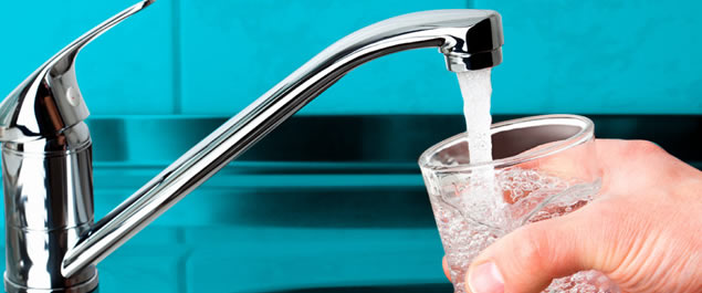 llave de agua abierta, llenando un vaso de vidrio