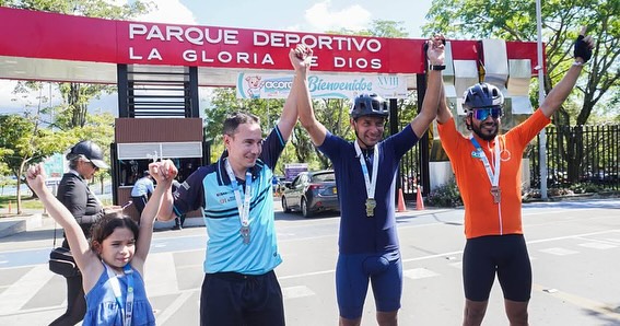 Grupo de competidores con manos en alto, en señal de victoria.