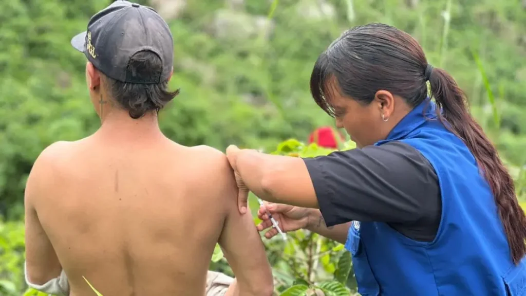Persona vacunando a un campesino.