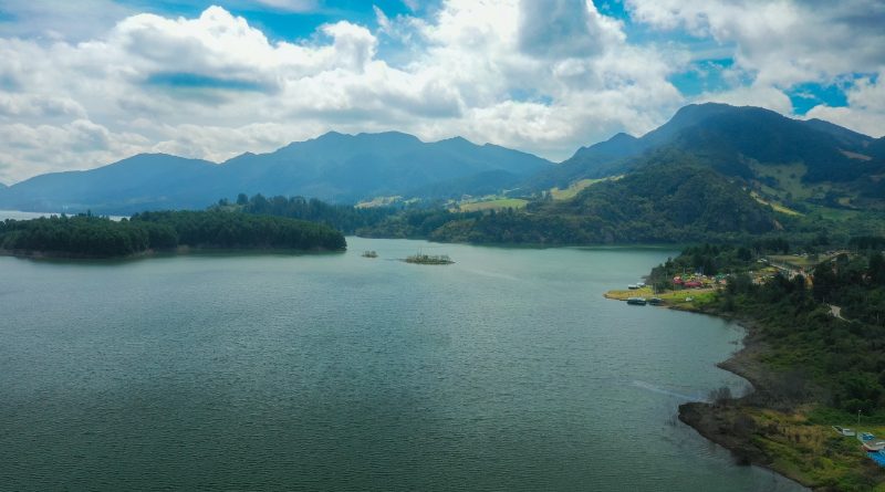 Panorámica del embalse del Neusa rodeado de montañas y verdes campos.