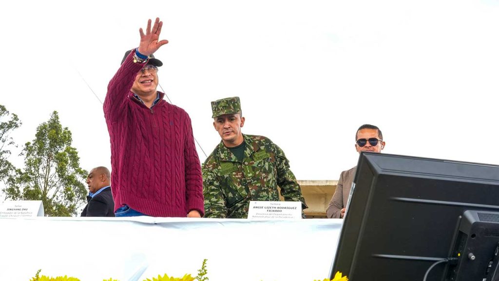 Presidente de Colombia, junto a Militar. El presidente deja una mano arriba.