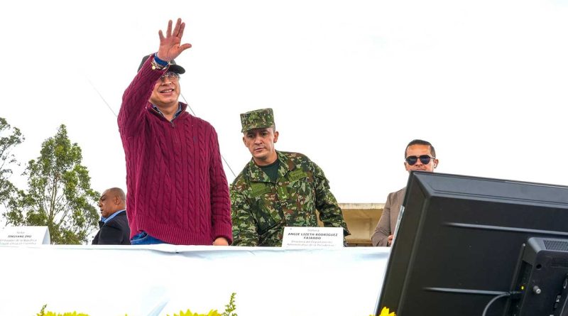 Presidente de Colombia, junto a Militar. El presidente deja una mano arriba.
