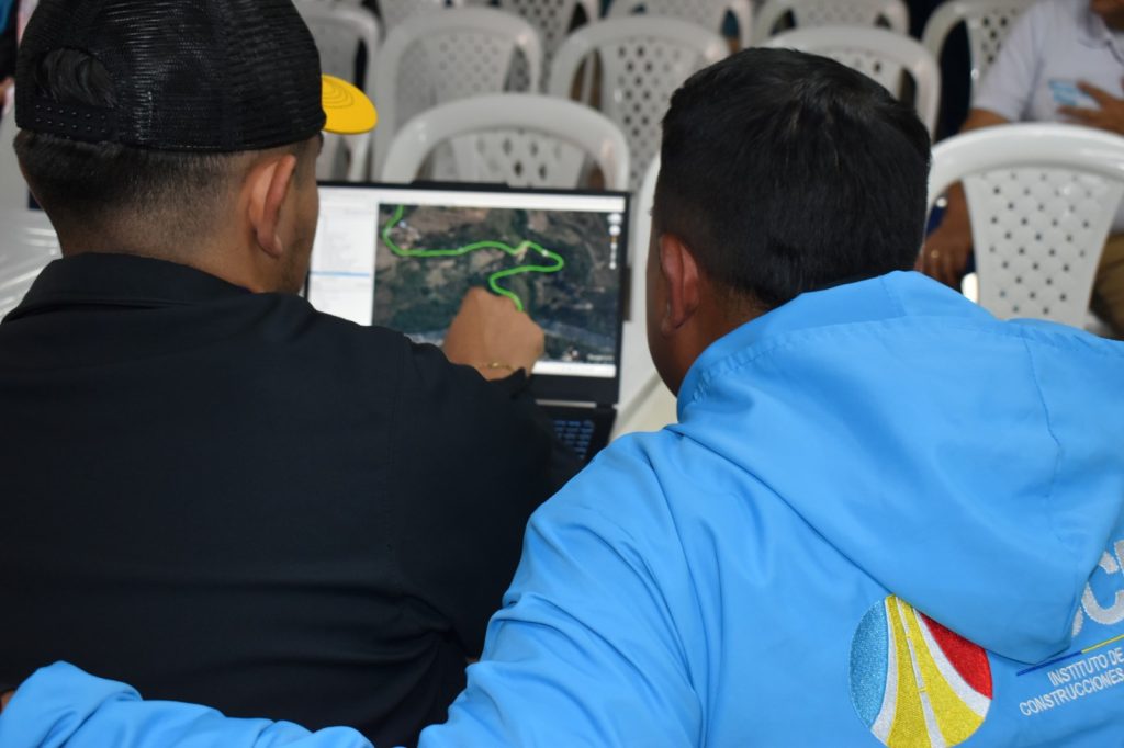Equipo de trabajo de la Unidad Nacional de la Unidad de Riesgo, revisando imágenes de mapas en el computador