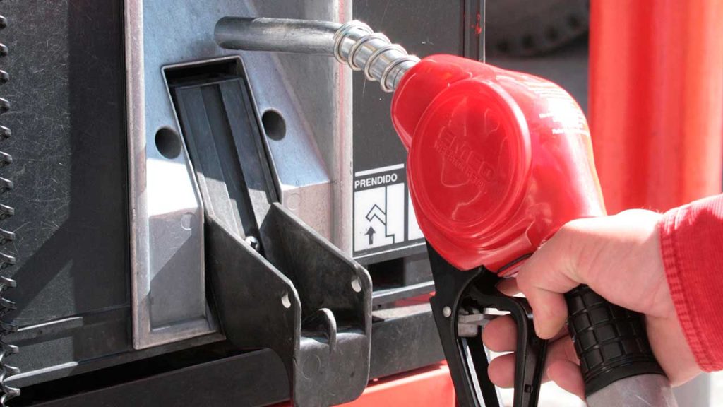 Dispensador de gasolina de color rojo, con una mano sosteniéndolo.
