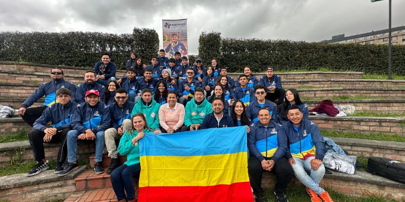 Grupo de jovenes deportistas llevan en la mano la bandera de Cundinamarca.